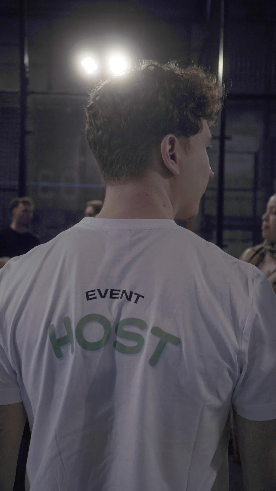 An athme event host in a HOST shirt looking out over a padel launch night