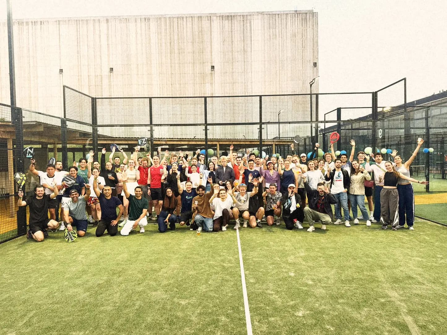 Over a hundred athme players cheering on a padel court in Copenhagen after a community padel party