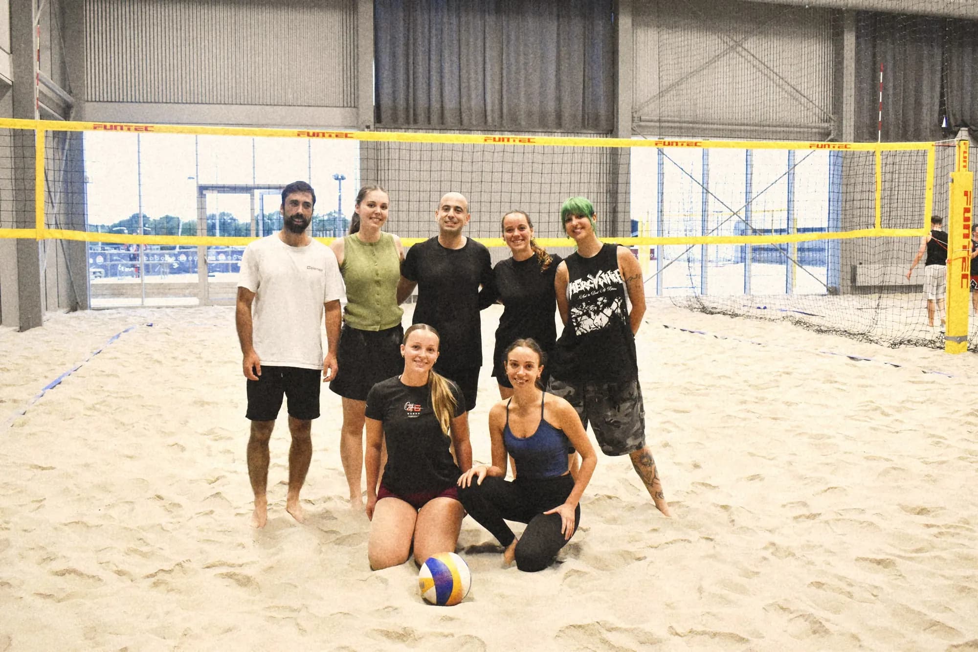 An athme beach volleyball crew posing together on the sand in Copenhagen