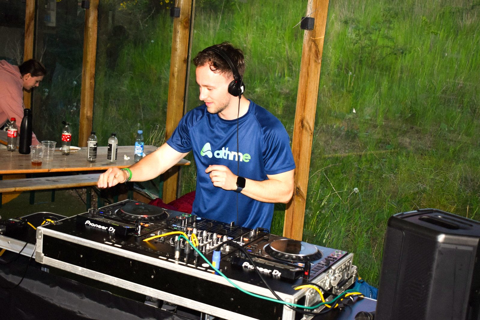 Octavian DJing at an athme padel party in an athme shirt